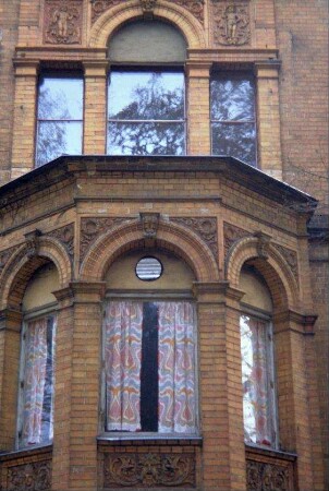Detail des ehemaligen Schlosses: Fenster mit verzierten Brüstungsfeldern, Reliefsteine in den Zwickeln