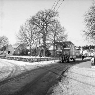Tremsbüttel-Dorf: Dorfplatz mit Ehrenmal: dahinter Bauern- und Wohnhäuser: vorn Dorfstraße: rechts landwirtschaftliches Fuhrwerk und Fahrradfahrer: Winter