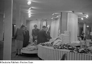 Fachbesucher an einem Messestand mit Stoffen