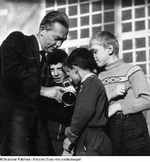 Fotograf Erich Pohl (1904-1968) mit Kindern, denen er seine Kamera vorführt. Dresden?