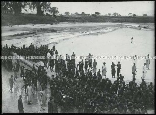 Afrikaner beim Transport eines Baumstammes am Strand