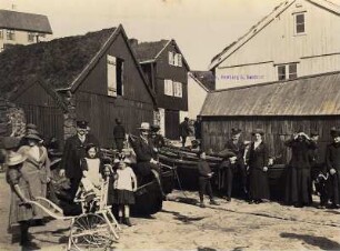 Thorshaven/Färöer Inseln (Dänemark). Gruppenbildnis von Touristen mit einheimischen Kindern am Hafen, vorn Mädchen mit Kleinkind im Kinderwagen