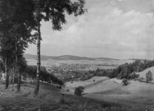 Ort mit zahlreichen Industrieschornsteinen vor bergiger Landschaft