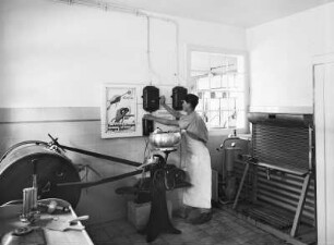 Dresden. II. Internationale Hygiene-Ausstellung. Raumaufnahme mit einem Arbeiter und einer Maschine mit daneben installiertem Motor-Schutz-Schalter