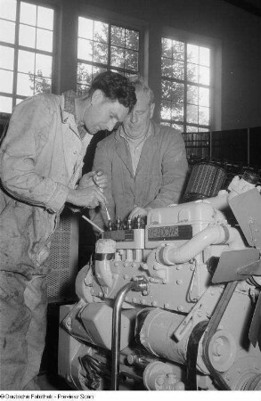 Zwei Arbeiter während des Aufbaus eines Dieselmotors