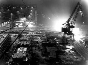 Hamburg-Finkenwerder. Eine Helling der Deutschen Werft bei Nacht. Im Vordergrund wird ein Schiff montiert.