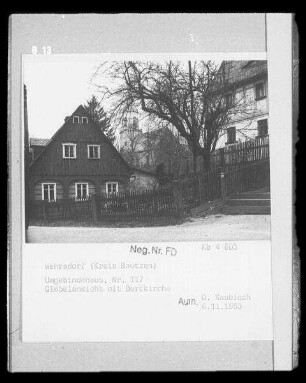 Sohland an der Spree-Wehrsdorf, Lessingstraße? Wohnhaus (Umgebindehaus; ehemals Nummer 117). Giebelansicht mit Einfriedung. Blick zur St.-Trinitatis-Kirche