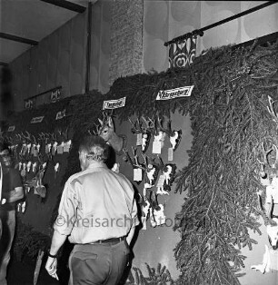 Kreisjägerschaft Stormarn e.V.: Rohlfshagen/Kupfermühle: Gastwirtschaft "Kupfermühle": Saal: Mitgliederversammlung: Ausstellungstafel mit Auswahl an Jagdtrophäen aus den Hegeringen: vorn links Personen