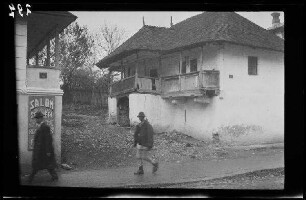 Câmpulung (Rumänien): baufälliges Wohnhaus mit 2 Balkonen, im Vordergrund auf einem Fußweg zu Passanten ("in Câmpulung")