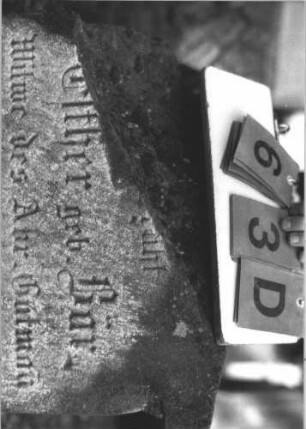 Grabstein 63 (Index: 99786687) Zustand: Inschrift oben rechts abgebrochen, z. T. verwittert, leicht eingesunken Maße HxBxT: 60x55x20 cm: Grabstein 63D