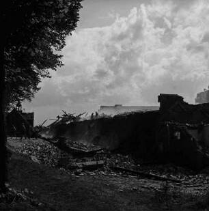 Gut Altfresenburg: Brand des Bullenstalls: Brandruine mit eingestürztem Dach und Rauchschwaden: darauf zwei Feuerwehrleute: davor Brandschutt: hinten links Personen, Torhaus mit Türmchen: Bäume: 24. August 1971
