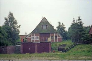 Sühlen: Zur Trave: Bauernhaus mit Reetdach: Giebelseite ehemaliger Wirtschaftstrakt mit Scheunentor: im Vordergrund Garagen