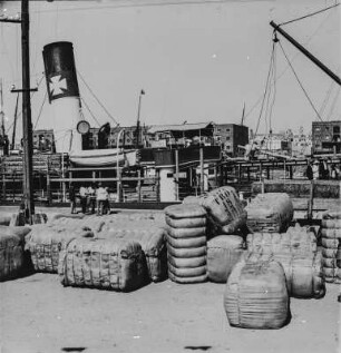 Am Hafen : Transportgüter werden von der Anlegestelle auf ein Schiff verladen