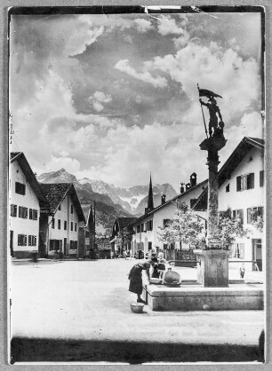 Am St. Floriansbrunnen in Parthenkirchen, wenn die Sonne hinter die Berge sinkt