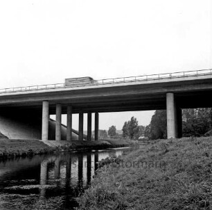 A 1: bei Reinfeld: Travebrücke bei Autobahnraststätte "Trave": Seitenansicht: Trave, mit Spiegelung der Betonpfeiler: oben auf Brücke Lkw [bewegungsunscharf]
