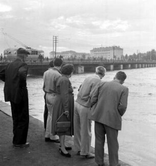 Schaulustige am Ufer eines Hochwasser führenden Flusses