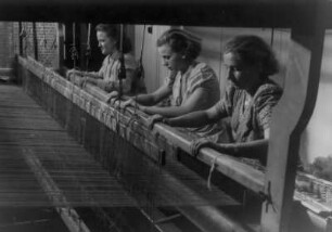 Weberinnen an einem mechanischen Webstuhl bei der Arbeit. Aufgenommen 1940