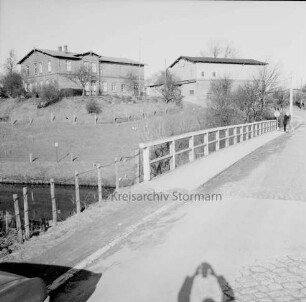 Bauernhäuser am Hang über Trave: vorn Brücke: hinten rechts Kind mit Fahrrad