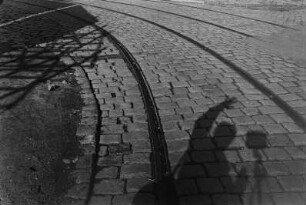 Straßenbahnschienen im Pflaster mit Schattenselbstbildnis des Fotografen