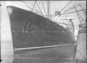 Seitenansicht des im Hafen festgemachten Hochseepassagierdampfers "Bremen", Schriftzug und Wappen des Norddeutschen Lloyd am Bug