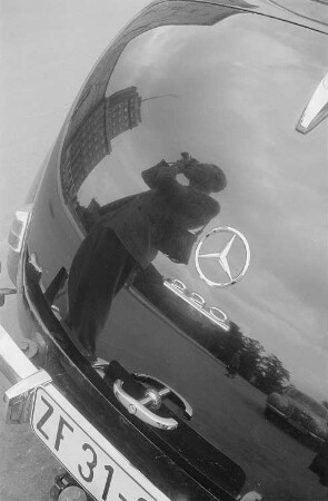 Roger Rössing spiegelt sich beim fotografieren im Heck eines Mercedes