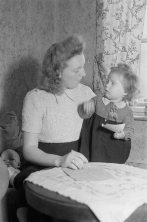 Reportage: Berliner Männer und Frauen tragen sich für die Ächtung der Atombomben ein : Mutter mit Kind trägt sich in die Unterschriftenliste ein