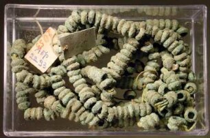 Große Kette aus kleinen runden Ringen, die zum Teil noch auf dem antiken Faden gereiht sind. Ein Teil modern aufgereiht