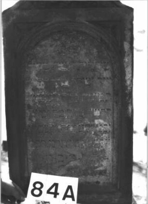 Grabstein 84 (Index: 99898849) Material: Sandstein Zustand: stark verwittert Maße HxBxT: 142x52x24 cm Beschreibung: aufgesockelte Stele, Konvexbogenabschluss mit Voluten und Mittelpalmette Symbolik: Voluten, Palmette: Grabstein 84A