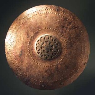 Brustplatte mit Buckeln, Linienornamenten und eingepunzten Tierfiguren verziert. Dazu die sonst fehlende kleine durchbrochene ornamentale Mittelplatte. Auf der Rückseite Reste von den Schulterriemen