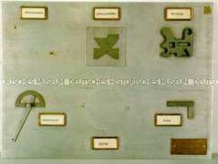Lehrtafel: Formteile und Geräte auf Metallplatte