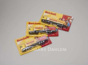Drei Verpackungen mit Spielzeug-Lastzügen von "Reichelt"