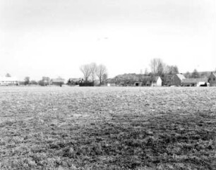 Oberlausitz. Landschaftsschutzgebiet Königshainer Berge. Blick über ein Feld gegen Gehöfte einer Ortschaft