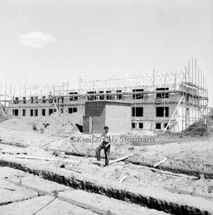 Wohnungsbau: Wohngebiet Kellerberg-Süd: Wohnblocks mit Gerüsten im Bau: davor Arbeiter in Fundament