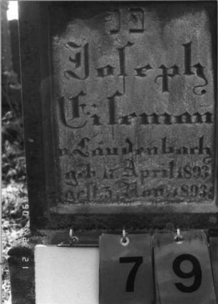Grabstein 79 (Index: 100116224) Material: Sandstein Zustand: gut Maße HxBxT: 100x35x21 cm Beschreibung: aufgesockelte Stele mit eingezogenem Segmentbogenabschluß und Aufsatz, eingetieftes Schriftfeld Besonderheit: Kindergrab: Grabstein 79A