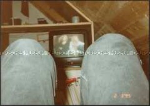 Zwischen zwei Hosenbeinen auf ein Fernsehbild fotografiert (Altersgruppe bis 14)