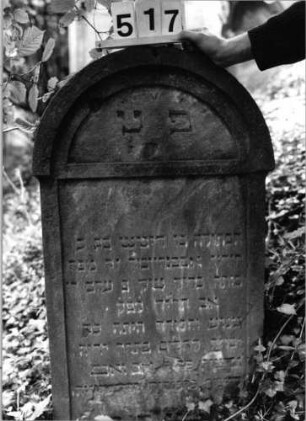 Grabstein 517 (Index: 99802698) Material: Sandstein Zustand: unten abgeblättert/Textverlust Maße HxBxT: 88x50x12 cm Beschreibung: Stele mit verdachtem Rundbogen, profilierter Rand, Giebelfeld: Grabstein 517