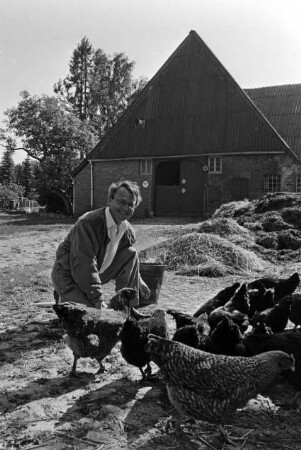 Hof von Günther Fielmann: Besitzer hockend neben Misthaufen und Hühnern: im Hintergrund Scheune