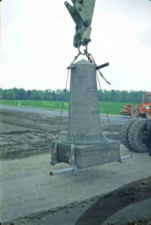 Bargfeld-Rögen: bei Elmenhorster Straße: Umsetzen von Meilenstein [Nr. 7]: Aufsetzen auf neuem Standort: Stein an Arm von Bagger