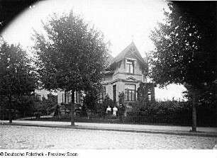 Villa, Straßenansicht mit den im Garten für den Fotografen posierenden Bewohnern