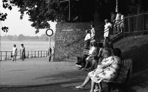 Düsseldorf-Kaiserwerth: sitzende Leute auf Rheinpromenade