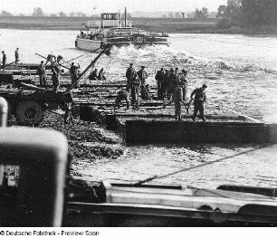 Deutschland . Nationale Volksarmee - Landstreitkräfte. Taktische Übung der Pioniertruppen. Bau einer Pontonfähre (?), im Mittelgrund ziviles Motorfrachtschiff