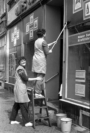 Schaufenster putzen : Zwei Verkäuferinnen die die Schaufenster des Gemischtwarenladens putzen