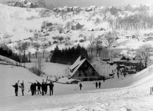 Deutschland. Winterurlaub im Harz. Blick auf das verschneite Sankt Andreasberg. Im Vordergrund Wintersportler. Aufgenommen 1963