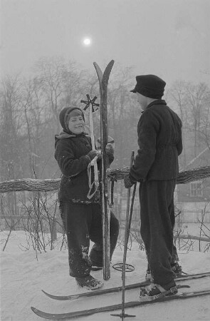 Leipzig, Johannapark. Kinder beim Ski- und Schlittenfahren, zwei Kinder mit Skiern im Gespräch