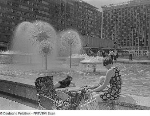 Wasserspiel mit Pusteblumen (Kugelbrunnen) : Dresden. Sich ausruhende Mutter mit zwei Kindern und Kinderwagen am Brunnenrand der Wasserspiele "Pusteblumen"