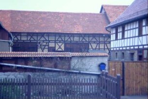 Blick über Hofmauer in einen Hof, hinten lange Scheune; Vorgarten