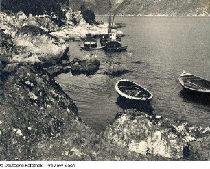 Fischerboot und Ruderboote an einer felsigen Küste