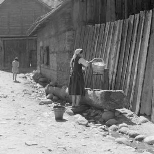 Alltagsbild. Frau in Ihrer Alltagstracht an einer Wasserstelle in Bansko am Fuße des Pirin-Gebirges