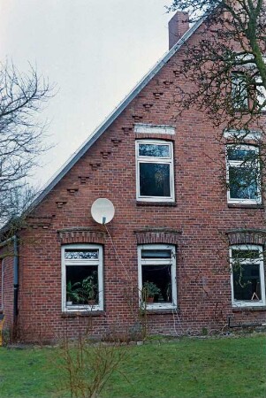 Hörn 23: Hofanlage: traufständiges Bauernhaus aus Backstein von 1874: Giebelseite Wohntrakt, Teilansicht: Fenster, unter Ortgang Treppenfries