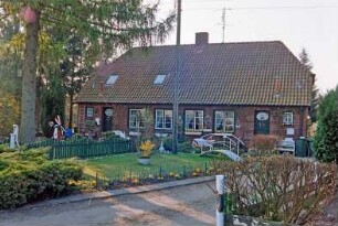 Blumendorf 4: traufständige Doppelkate aus Backstein: Straßenfront: Eingangstüren, Hausnummer, Sprossenfenster: Vorgärten, Baum, Strommast, Zäune, Hecken: vorne Einfahrt: 22. April 2003